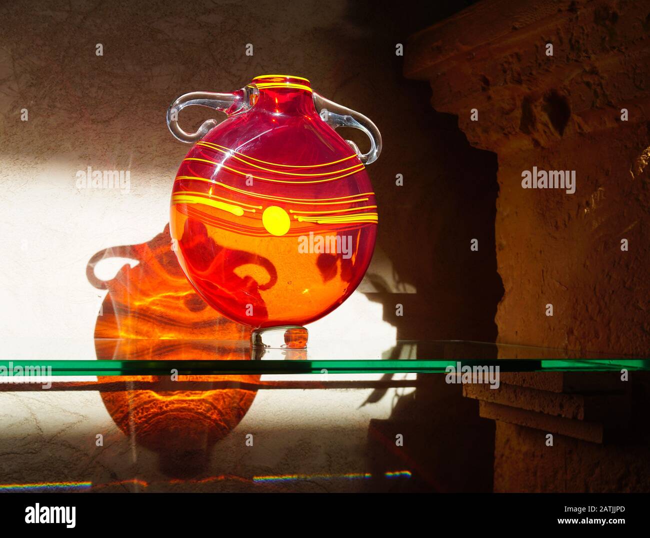 Un vaso in vetro crea ombre e riflessi incredibili mentre è illuminato dal sole del pomeriggio. Foto Stock