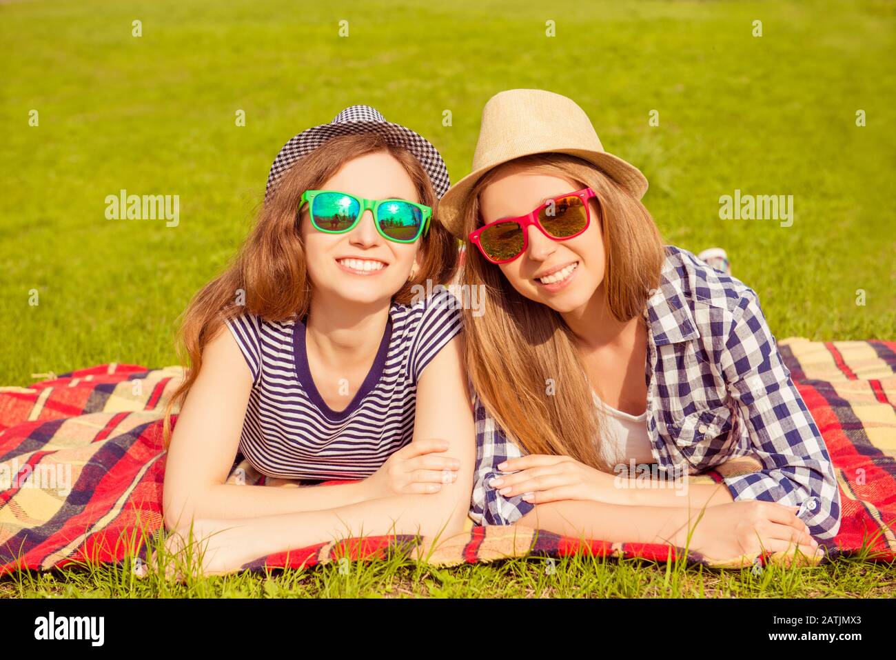 Ritratto di donne felici in estate cappelli e bicchieri sdraiati sul plaid nel parco Foto Stock
