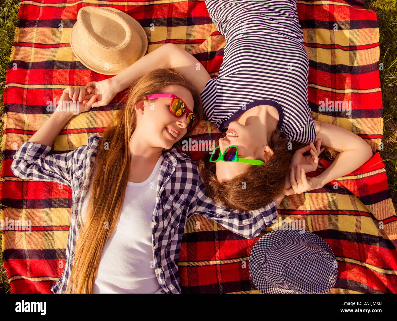 Vista dall'alto di due ragazze felici in occhiali stesi su plaid Foto Stock