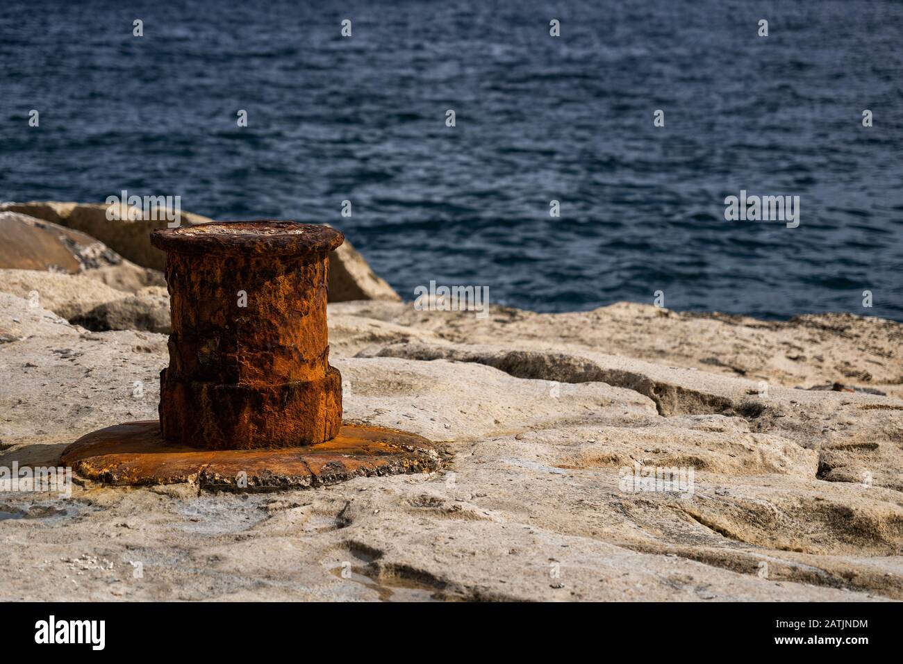 Un vecchio arrugginito paletto di ormeggio sul lungomare di Malta, profondità di campo poco profonda. Foto Stock
