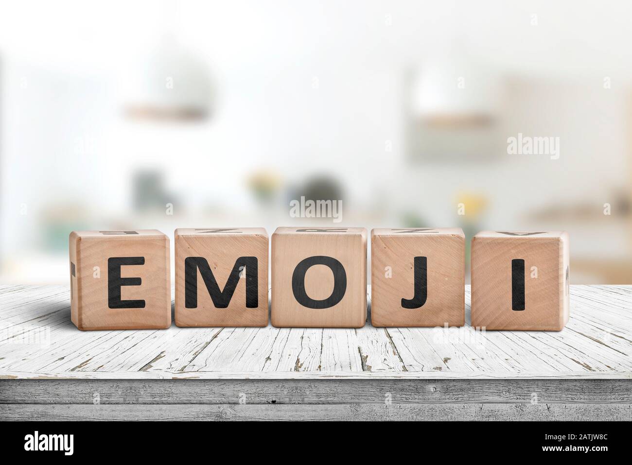La parola gli Emoji su un cartello in legno in una sala luminosa su una scrivania bianca Foto Stock