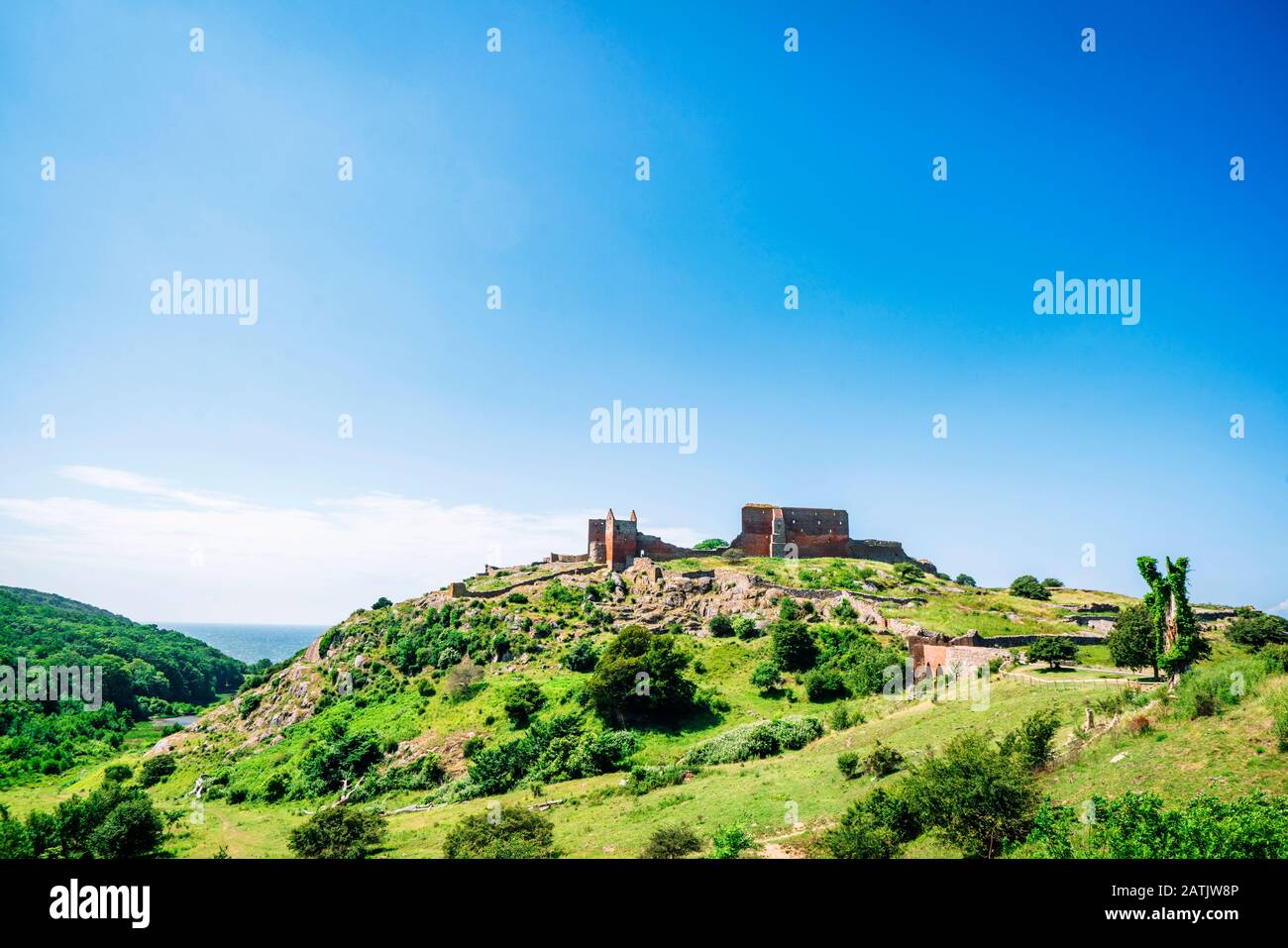 Rovina di un castello sulla cima af o verde collina in estate sotto un cielo blu Foto Stock