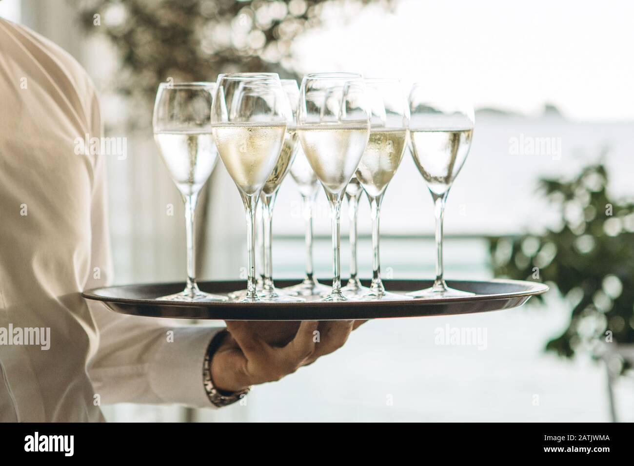Il cameriere tiene un vassoio con bicchieri di champagne o spumante bianco. Servizio nel ristorante. Foto Stock