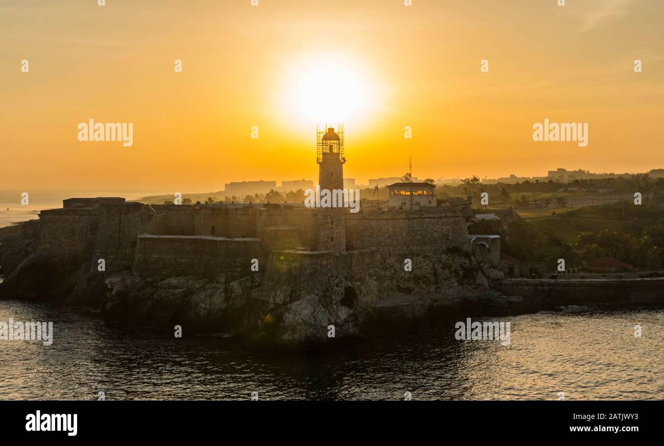 Il sole sorge appena sopra il faro situato nel castello di El Morro Cuba. Foto Stock