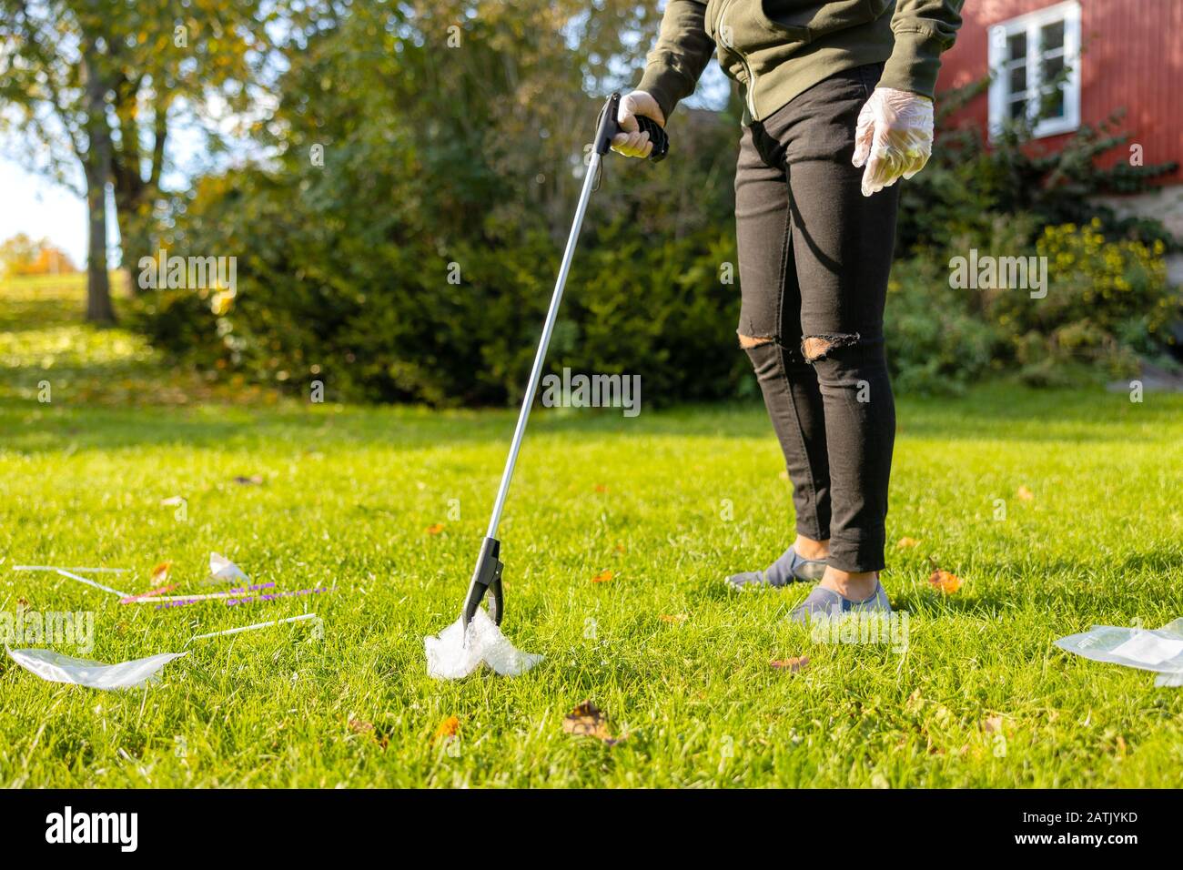 Giovane volontario maschio che raccoglie plastica dall'erba Foto Stock