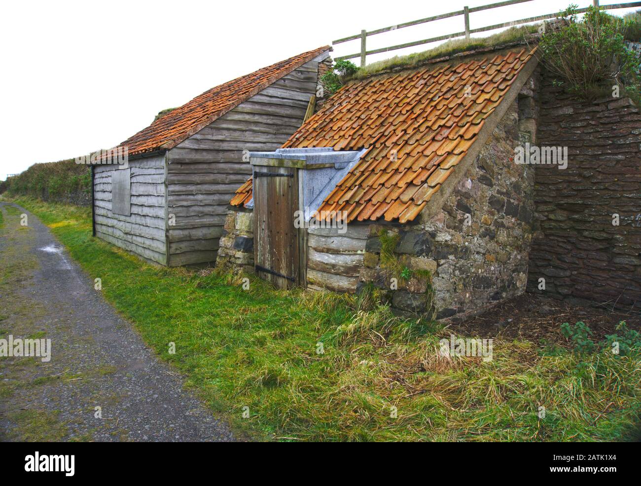 Capannoni in legno e pietra vicino al Castello di Lindisfarne, Holy Island, Northumberland, Regno Unito Foto Stock