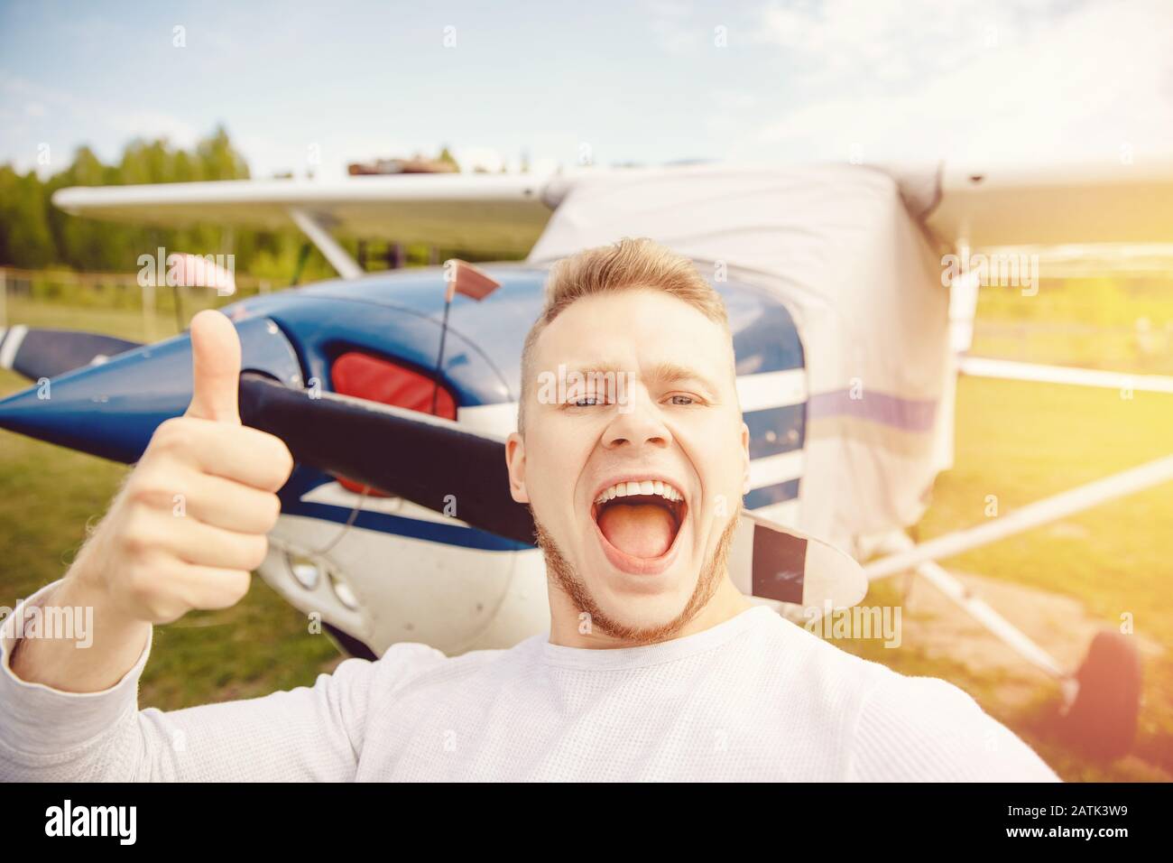 Felice pilota maschio selfie foto aviatore sorridente su sfondo elica guidato aereo. Concetto di noleggio di viaggi Foto Stock