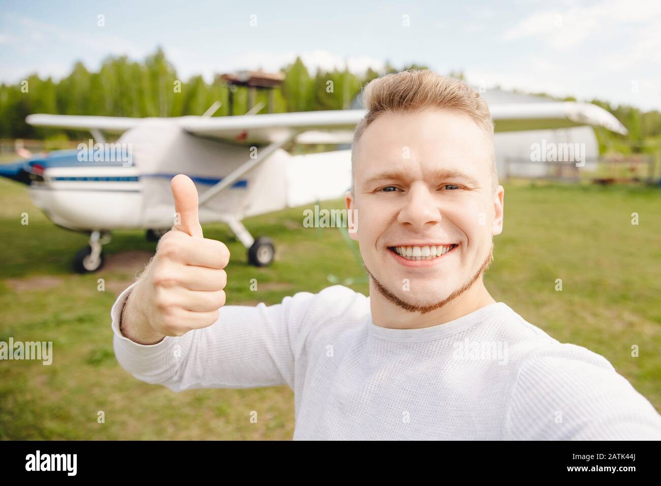 Felice pilota turistico fa selfie foto sullo sfondo dell'aereo. Concetto di viaggio con trasporto privato Foto Stock