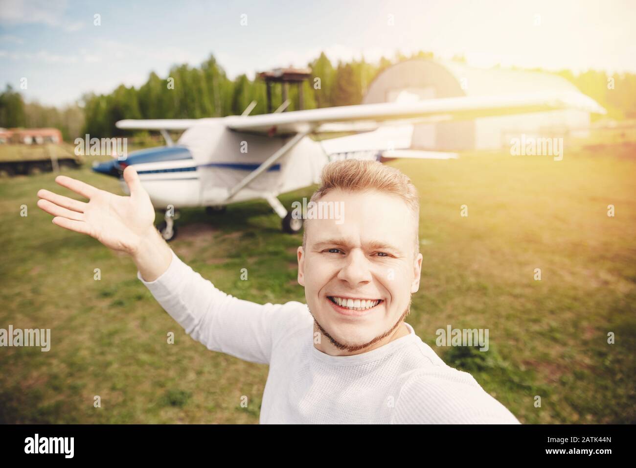 Felice pilota maschio selfie foto aviatore sorridente su sfondo elica guidato aereo. Concetto di noleggio di viaggi Foto Stock