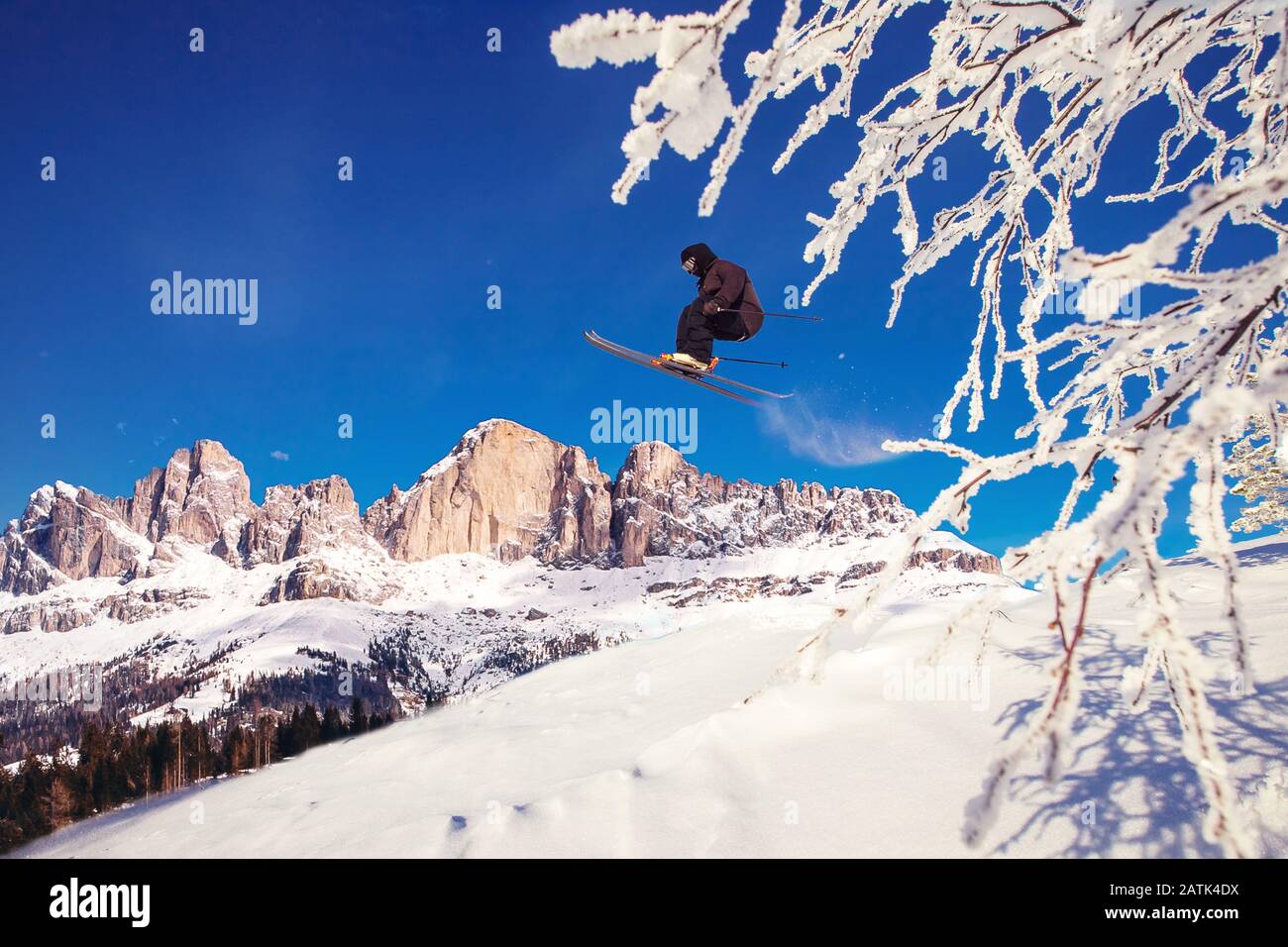 Lo sciatore salta in fresca freeride neve in montagna Alpi contro sfondo foresta Foto Stock