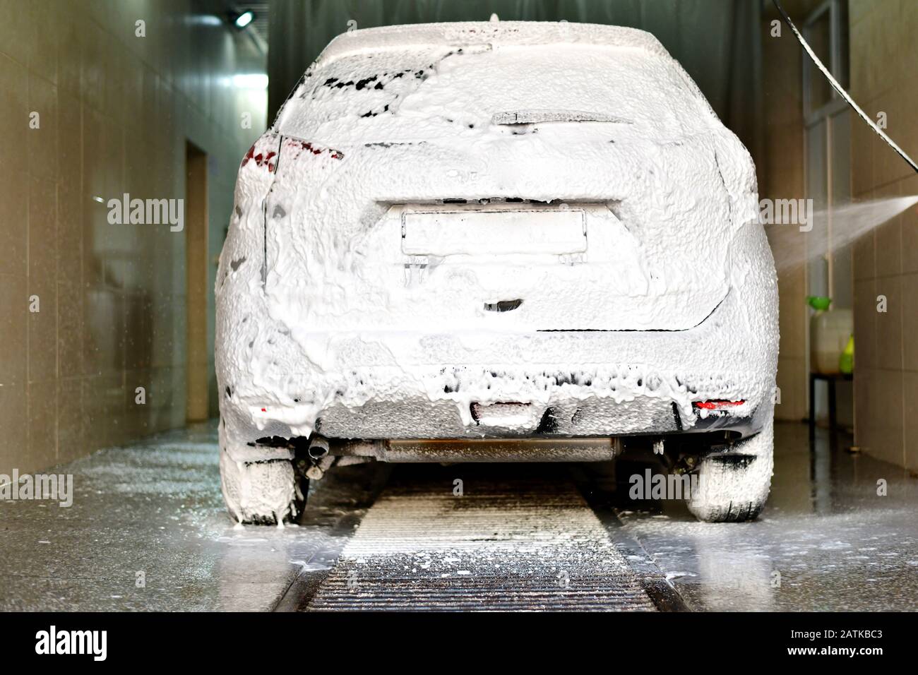 L'auto è coperta di schiuma e spray rivolti alla carrozzeria in camera per il lavaggio delle auto. Foto Stock