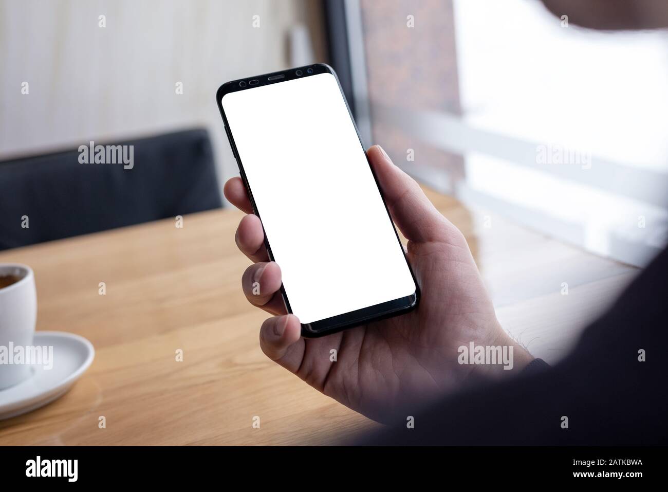 Immagine mockup della mano dell'uomo che tiene il telefono nero moderno con i bordi sottili Foto Stock