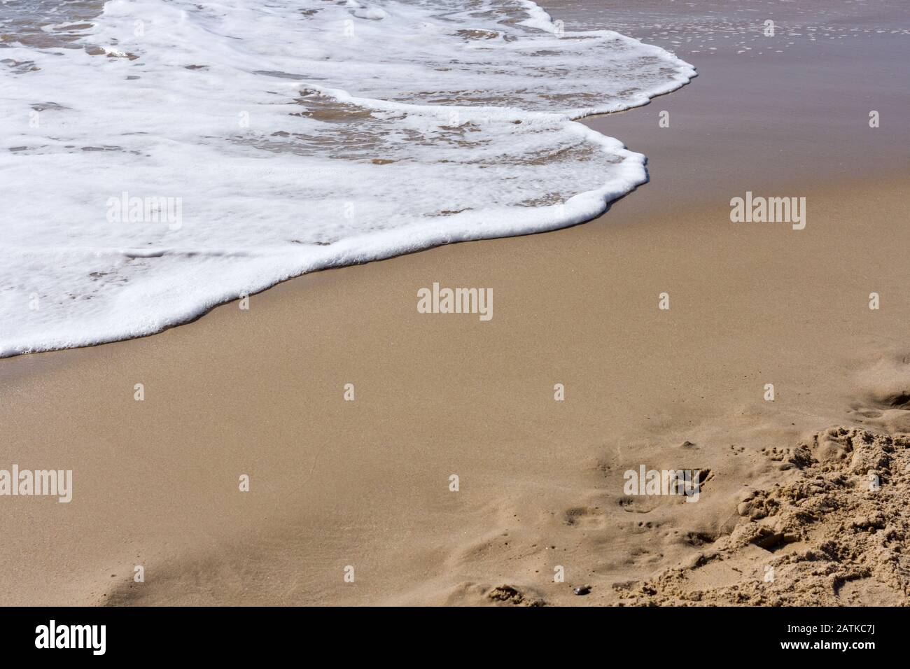 Primo piano di una spiaggia di sabbia con acqua schiumosa Foto Stock