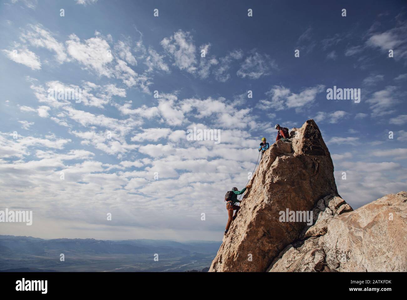 Tre scalatori di roccia ciascuno la cima di una montagna a Teton, Wyoming Foto Stock