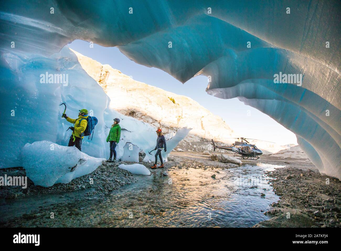 La guida alpina porta due clienti femminili nella grotta di ghiaccio per andare in arrampicata. Foto Stock