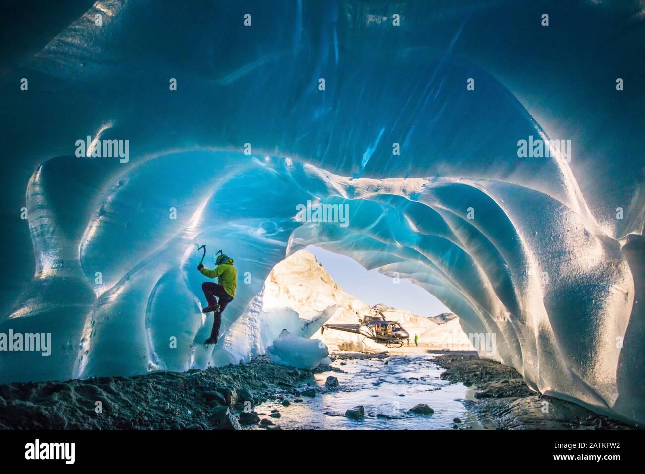 L'uomo ghiaccio sale all'interno della grotta glaciale durante il tour avventura in elicottero. Foto Stock