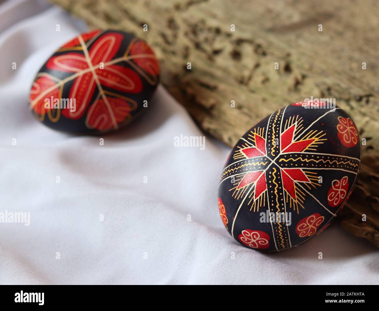 Due tradizionali uova di pasqua rumene isolate su sfondo bianco con tavola di legno, decorate a mano, simboli tradizionali, Europa orientale, spazio di testo Foto Stock