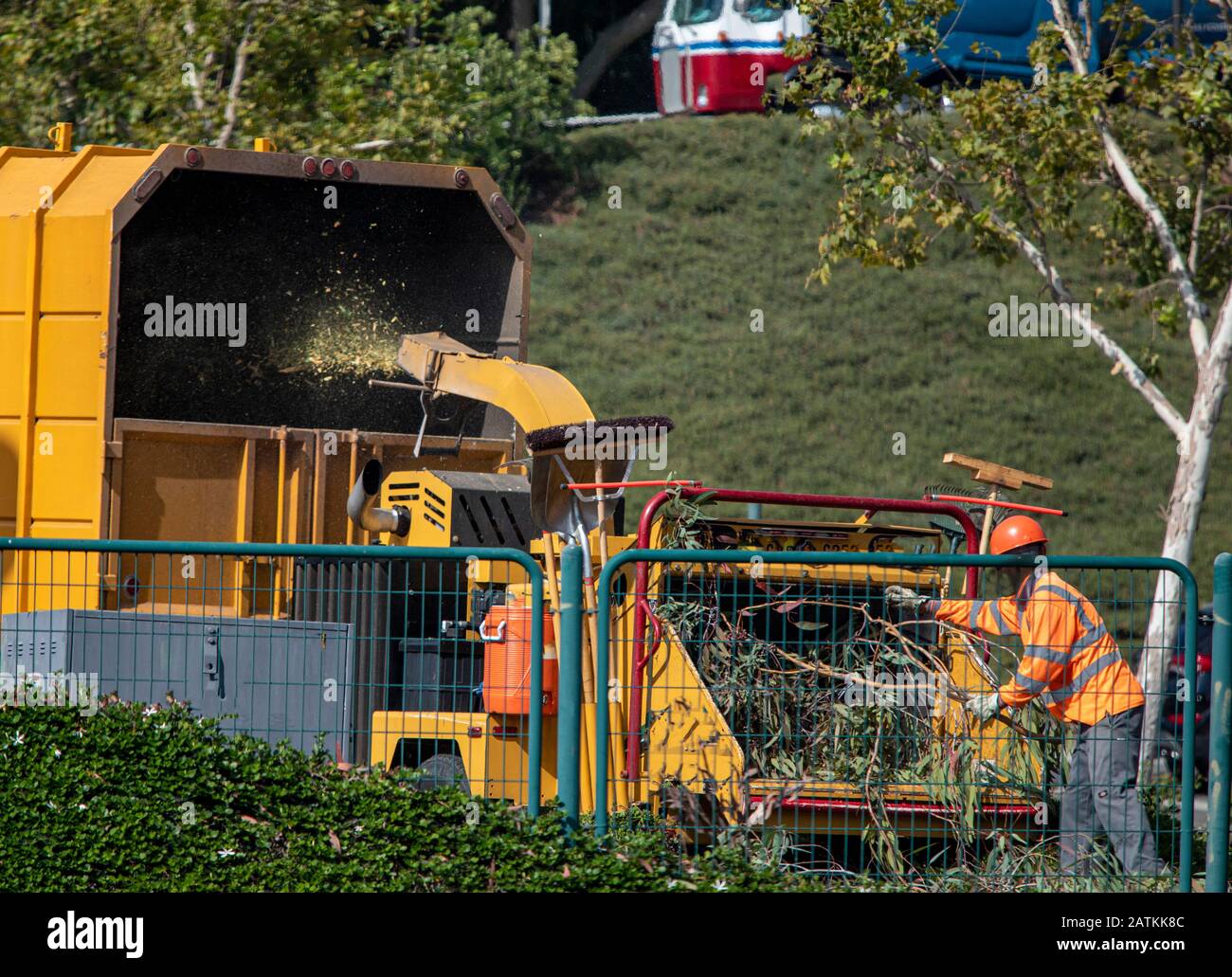 Uomo in giubbotto di sicurezza arancione e cappello duro arancione albero di funzionamento cassone ribaltabile albero di rettifica macchina in camion coperto giallo Foto Stock