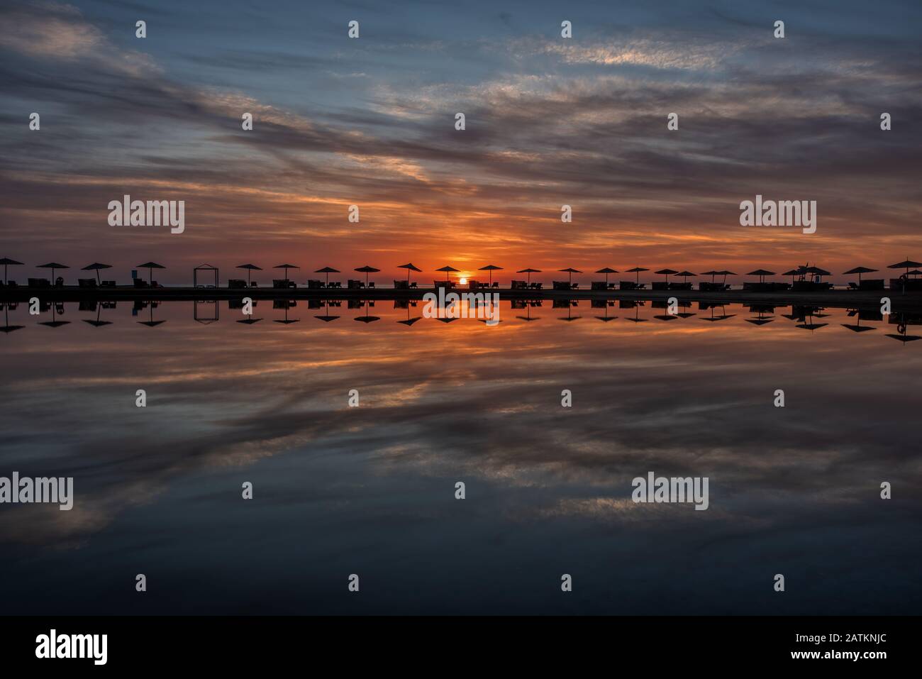 Fila di ombrelloni e lettini in piedi su una piccola isola allungata al tramonto, El Gouna, Egitto, 16 gennaio 2020 Foto Stock