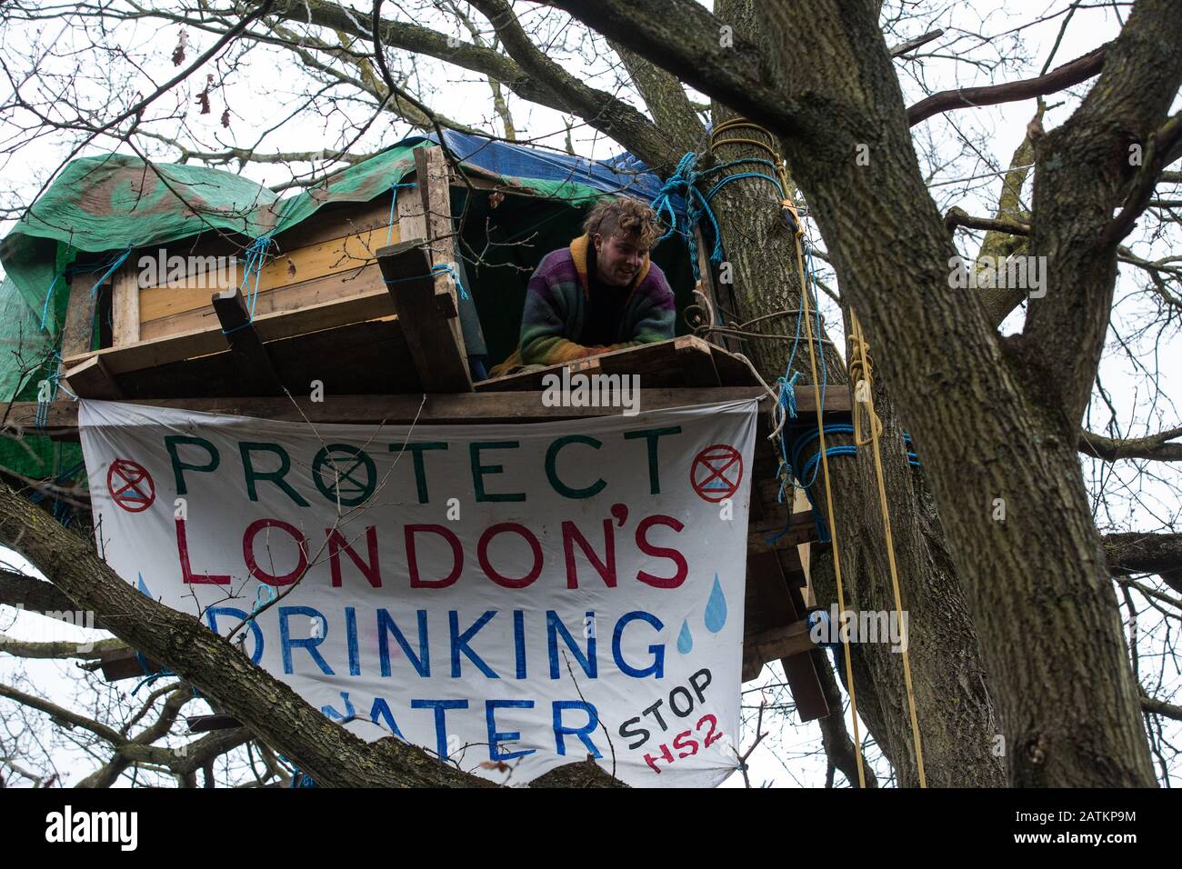 Harefield, Regno Unito. 3 Febbraio 2020. Un attivista si affaccia da una casa di trekking in alto in un albero alla sezione del campo boschivo di Harvil Road protezione della fauna selvatica campo. Gli attivisti ambientali di Save Colne Valley e Extinction Rebellion stanno cercando di impedire i lavori di costruzione per il collegamento ferroviario ad alta velocità HS2 nella Valle di Colne che richiederebbe il abbattimento di centinaia di alberi maturi. Credit: Mark Kerrison/Alamy Live News Foto Stock