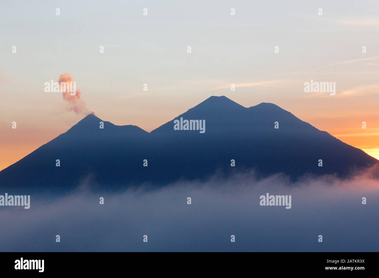 Tramonto con nuvole che circondano Volcan de Fuego e vulcano Acatenango Foto Stock