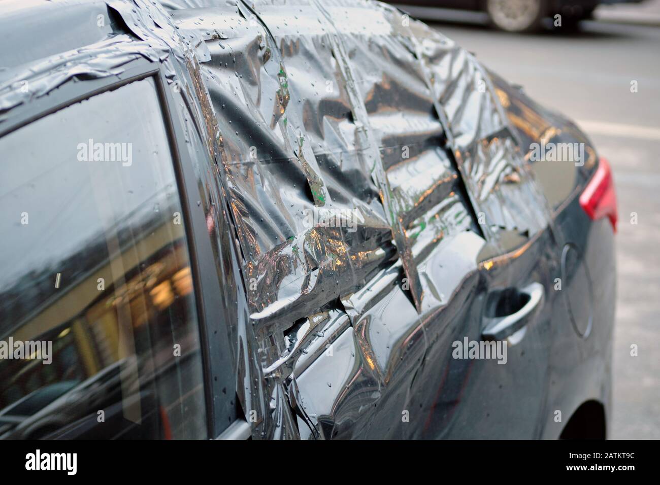 Vetro laterale posteriore rotto della vettura e incollato con nastro adesivo. Primo piano. Foto Stock
