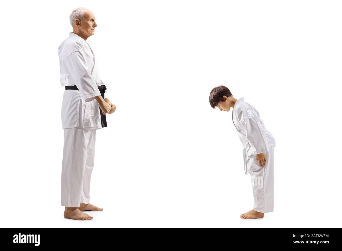 Profilo a tutta lunghezza di un ragazzo in karate kimono bowing di fronte al suo istruttore di karate anziano isolato su sfondo bianco Foto Stock