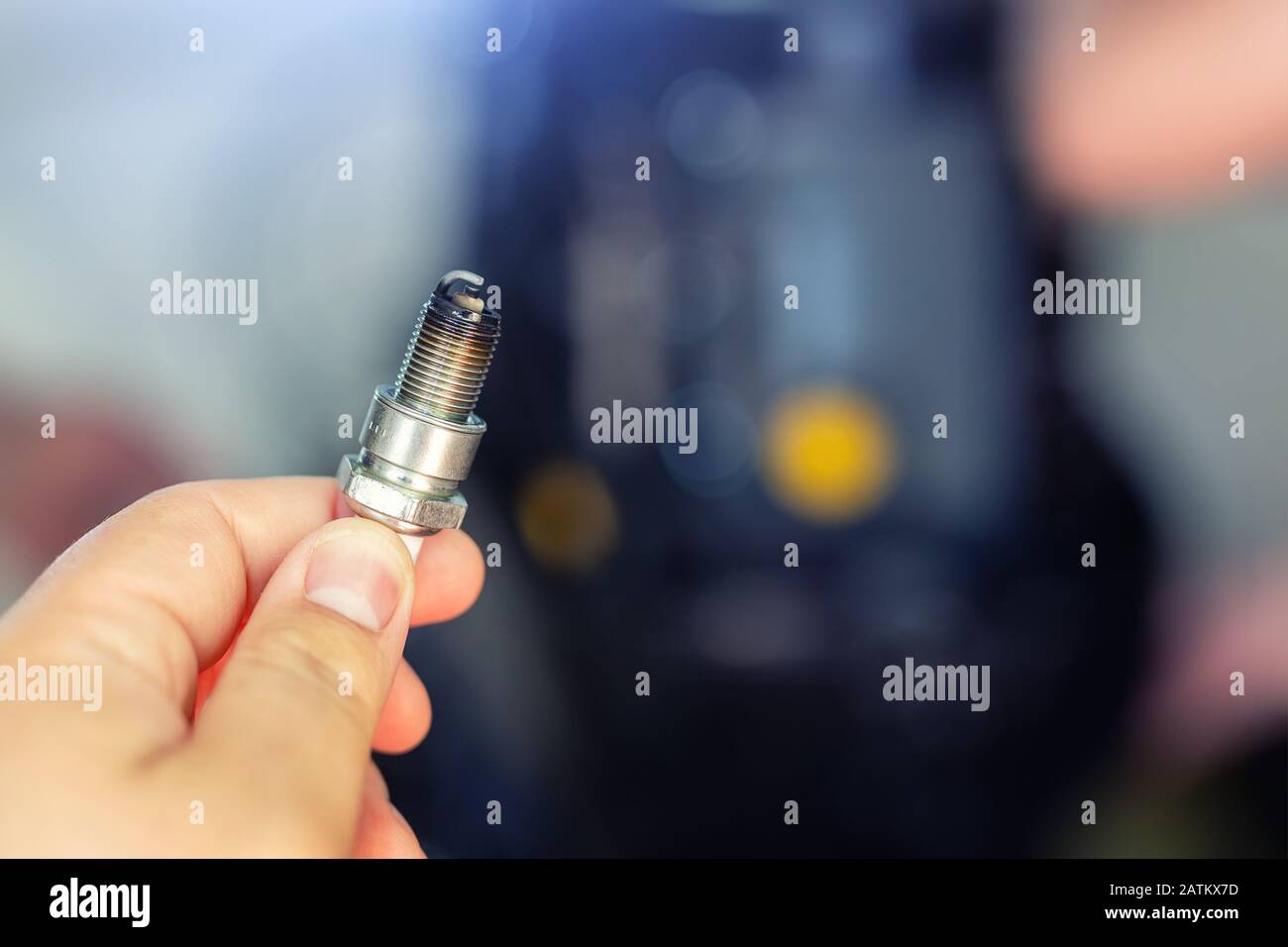 Durante la riparazione, la tenuta manuale di Machanic ha utilizzato una candela sporca con motore smontato su sfondo. Manutenzione e manutenzione stagionale del motore Foto Stock