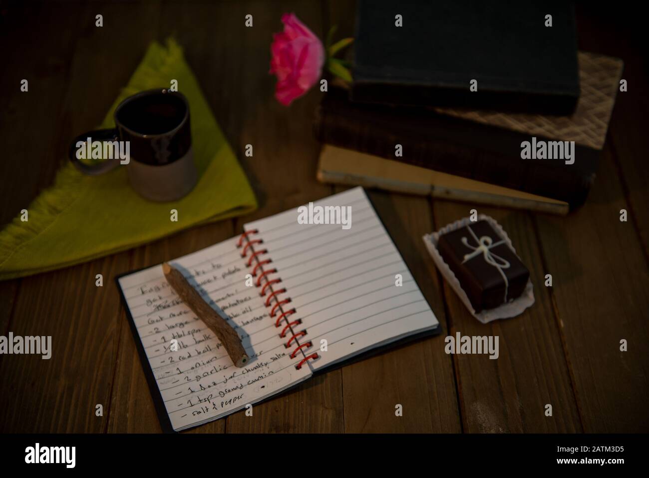Ricette giornale, matita, caffè e libri hardbound impilati su scrivania di legno, contro parete bianca - concetto di vita unplugged o vintage Foto Stock