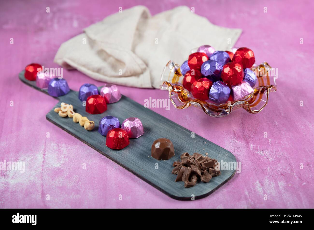 Cioccolato alla nocciola; cioccolato alla nocciola ricoperto di lamina rossa, viola e rosa su fondo lila di legno. EID al-Fitr (Festa del Ramadan) concetto. Foto Stock
