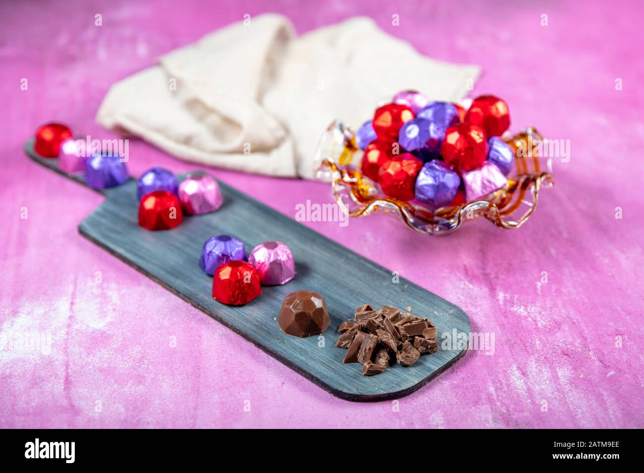 Cioccolato alla nocciola; cioccolato alla nocciola ricoperto di lamina rossa, viola e rosa su fondo lila di legno. EID al-Fitr (Festa del Ramadan) concetto. Foto Stock