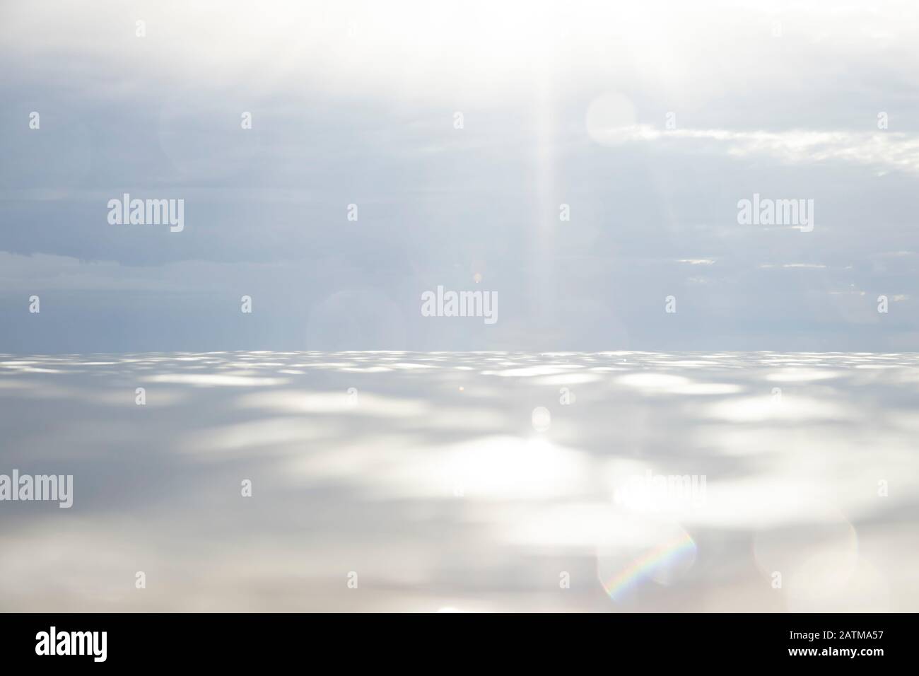 cielo d'acqua e orizzonte marino con nuvole drammatiche e sunflare Foto Stock