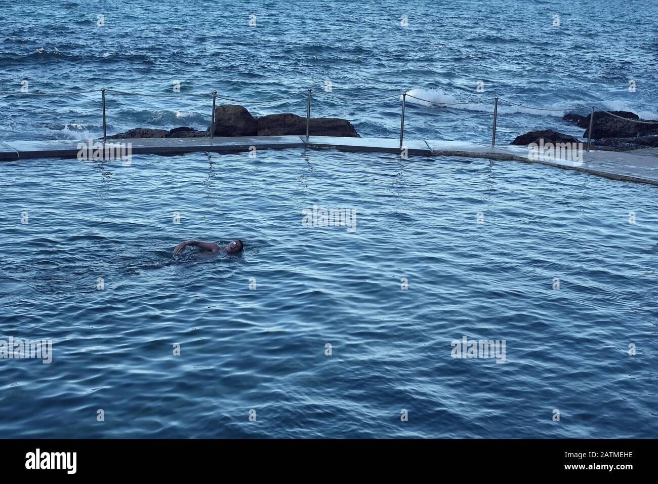 Un nuotatore solitario presso la piscina dell'Oceano Bronte Nella luce Del Mattino Foto Stock