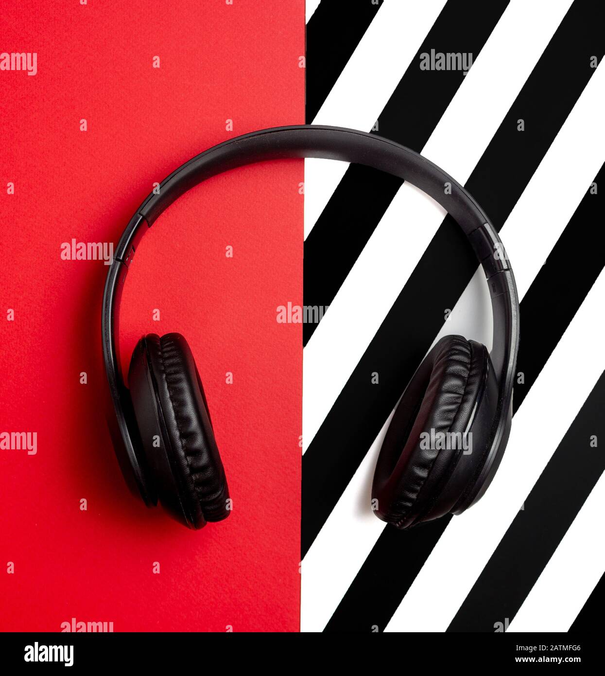 Cuffie nere su sfondo rosso. Concetto minimo. Disposizione piatta. Simulazione. Musica. Foto Stock