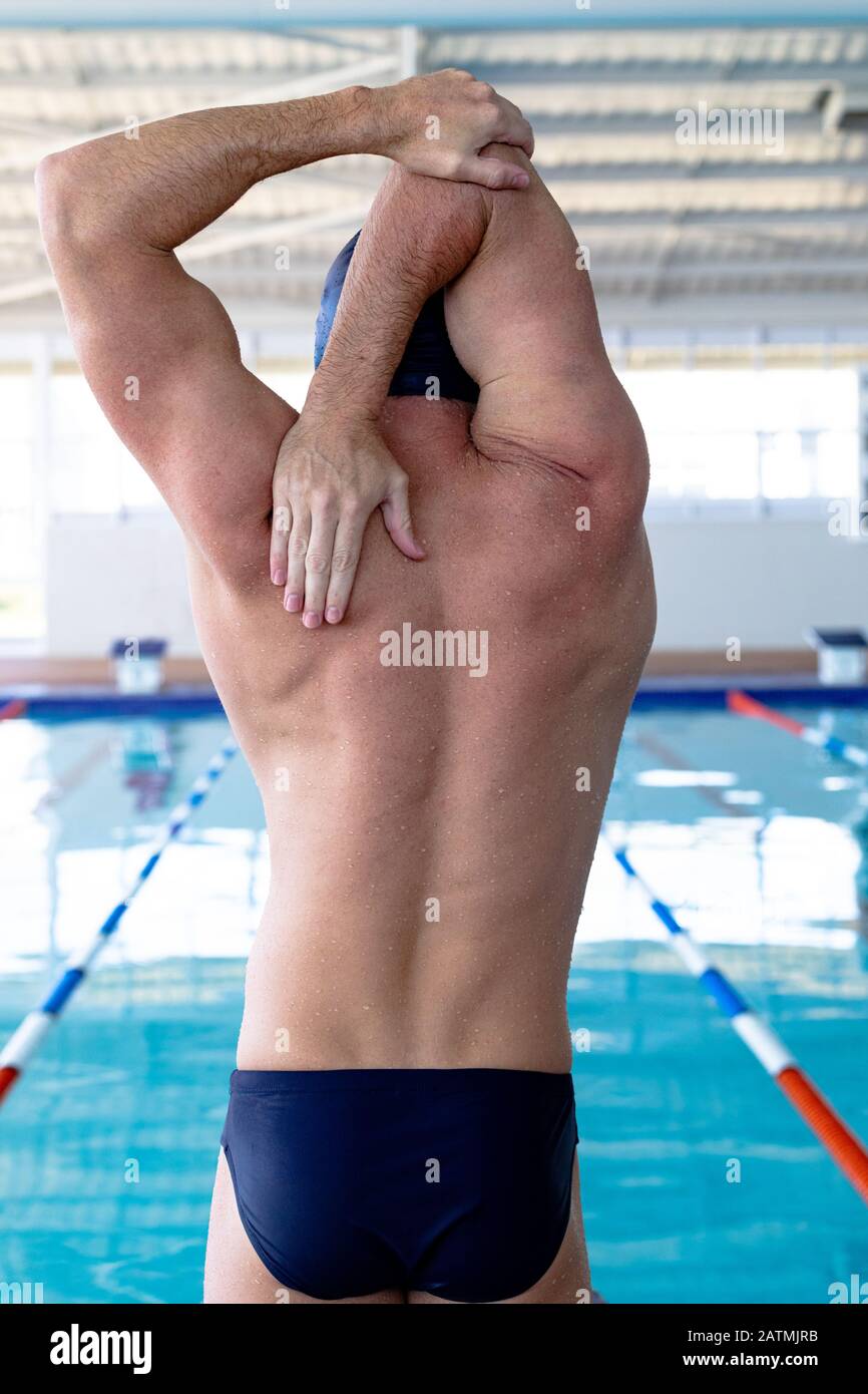 Nuotatore che si allunga di fronte alla piscina Foto Stock
