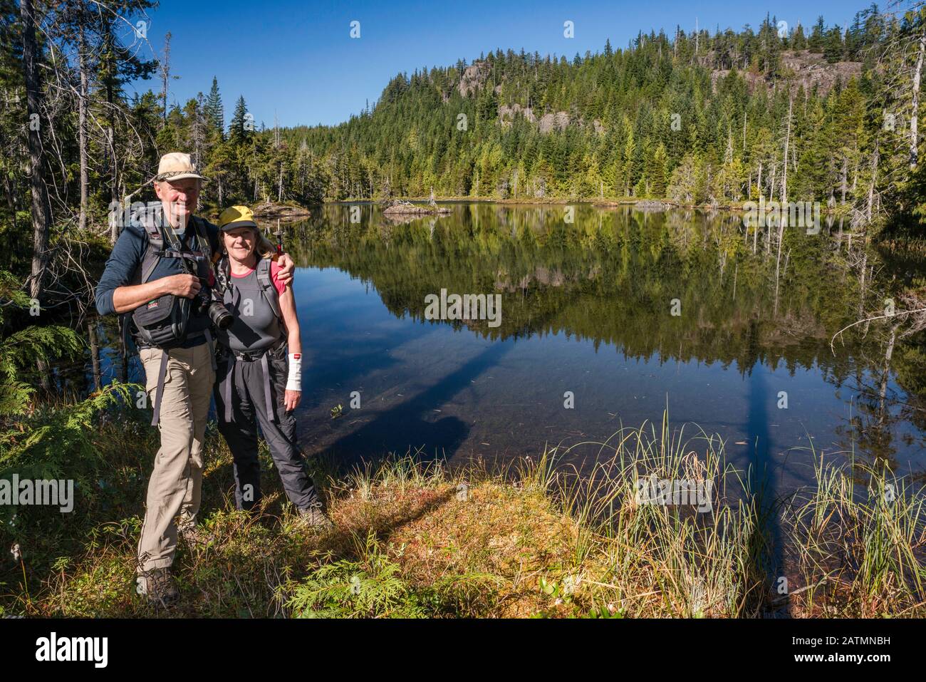 Escursionisti senior presso Il Lago Little Nugedzi nella foresta pluviale temperata, Quadra Island, British Columbia, Canada Foto Stock