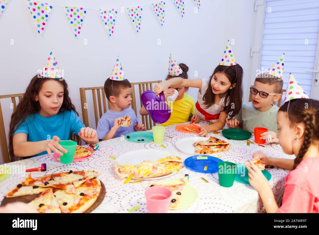 I bambini che mangiano la pizza al tavolo durante la festa di compleanno  Foto stock - Alamy