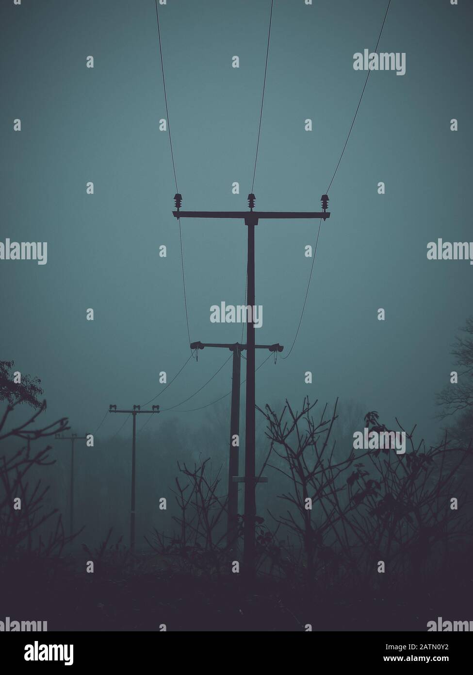 Linea di piccoli piloni di potenza attraverso la natura Foto Stock