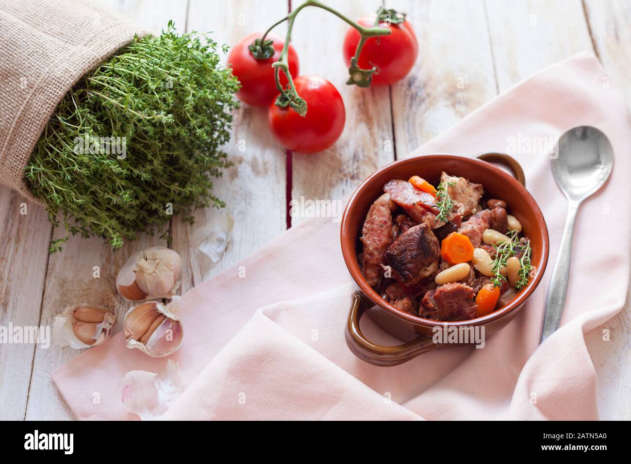 Cassoulet. Contenente salsicce di carne di maiale, oca, anatra e talvolta montone e due tipi di fagioli bianchi. Cibo francese. Su vecchio sfondo bianco di legno. Foto Stock