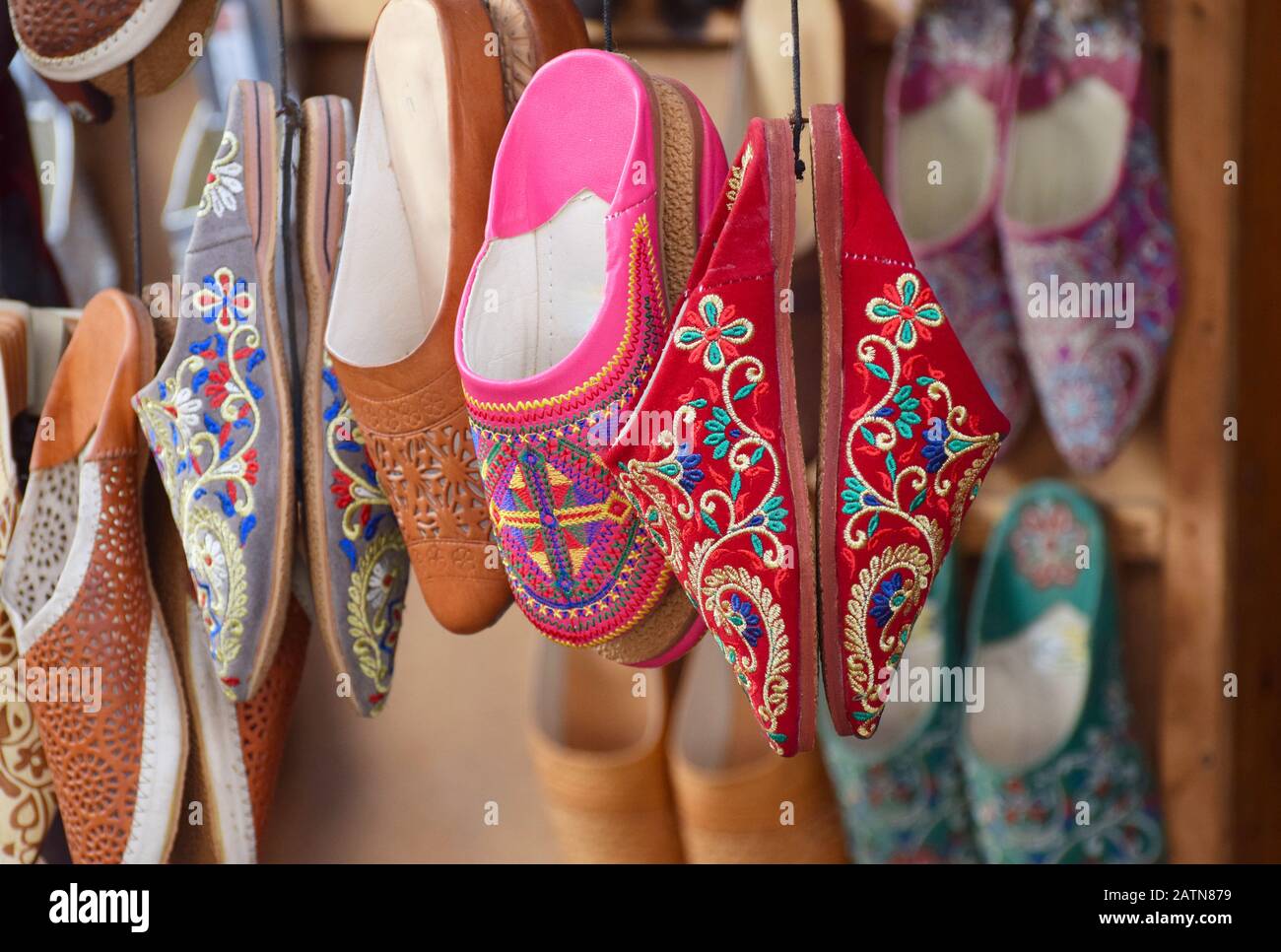 Pantofole marocchine ricamate dai colori vivaci chiamate ciabatte babouche appese a coppie su un mercato in un souk di Marrakesh Foto Stock