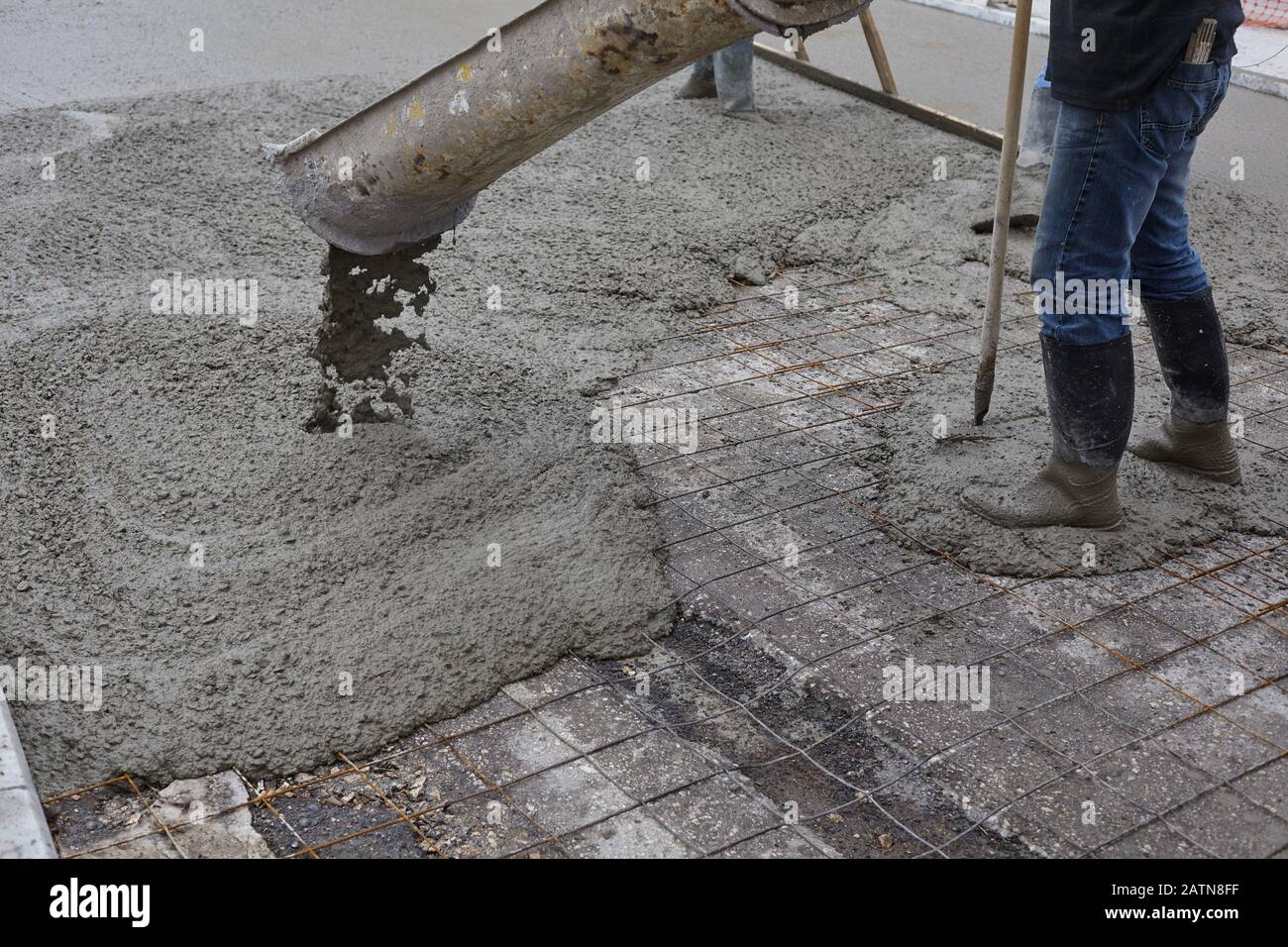 lavoratori che versano calcestruzzo bagnato usando benna di calcestruzzo. Costruzione industriale. Foto Stock