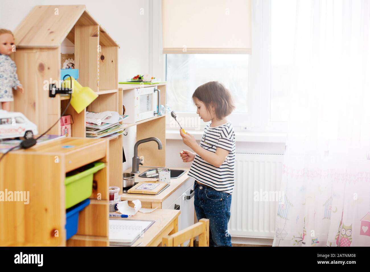 Bambina che gioca nella sua stanza del vivaio con giocattolo bambino`s stoviglie, cucina cibo in cucina giocattolo. Foto Stock