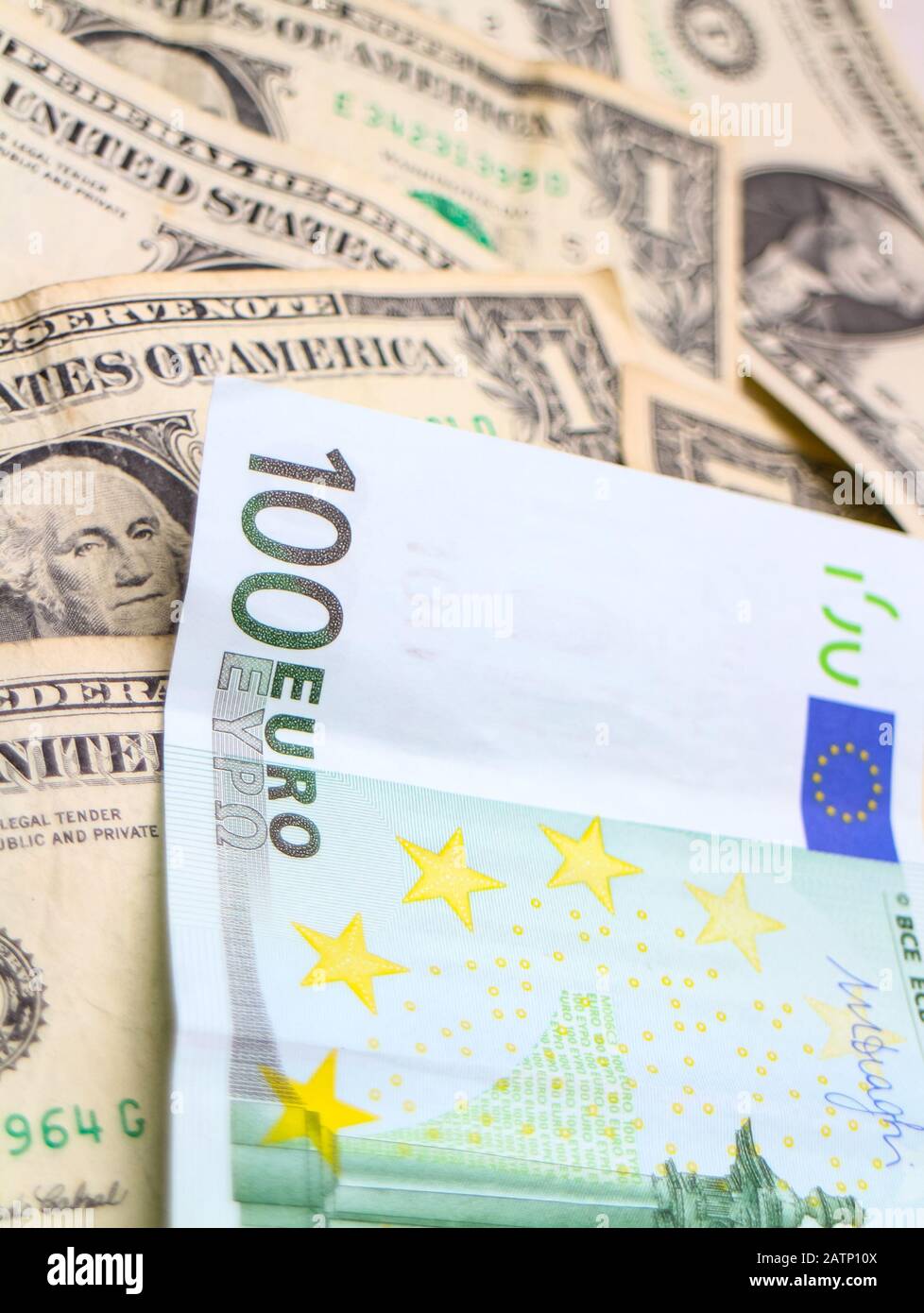 Una banconota da 100 Euro disposta su una pila di banconote in dollari USA. Foto Stock