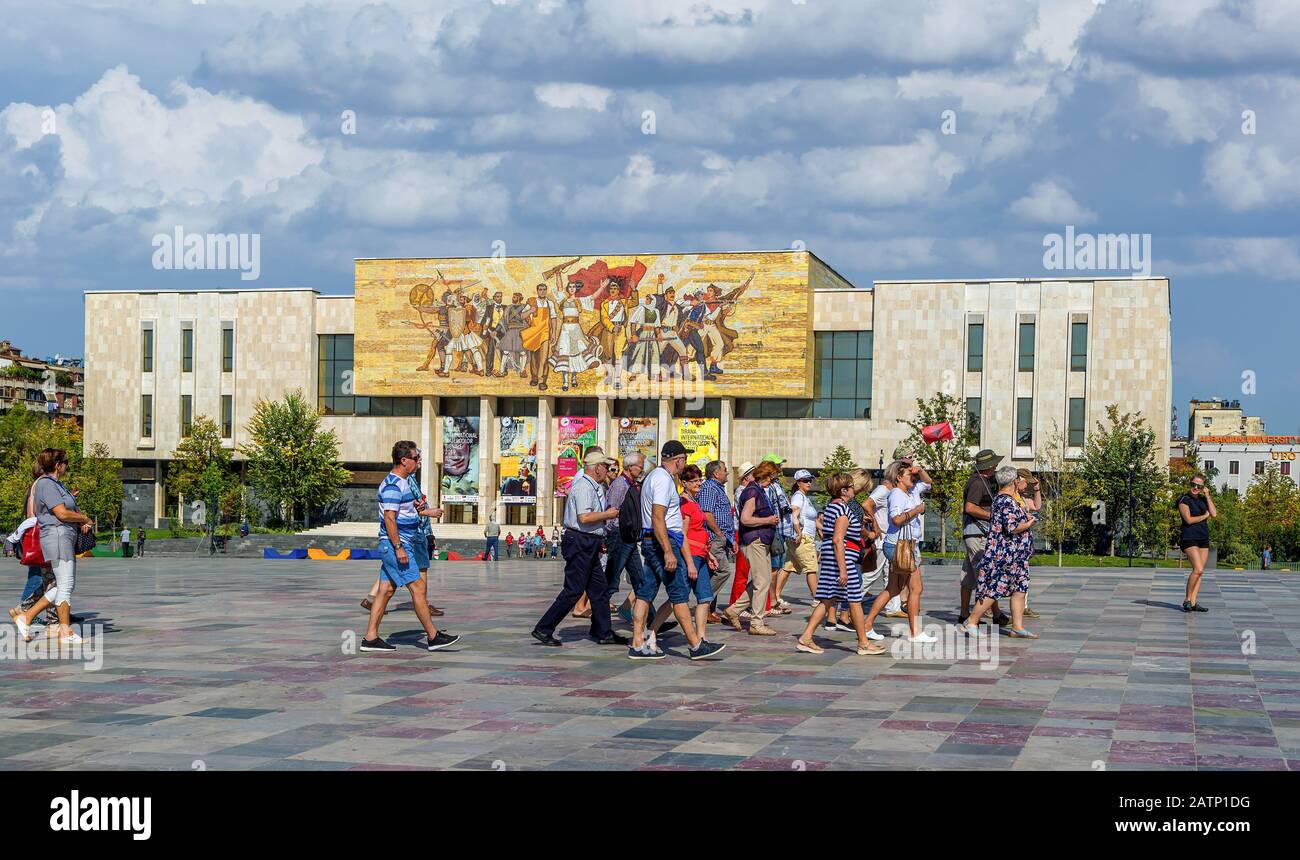 I turisti marciano in Piazza Skanderbeg di fronte al Museo Nazionale di Storia. Il Mosaico sopra il museo ha chiamato gli albanesi raccontare la storia della natio Foto Stock