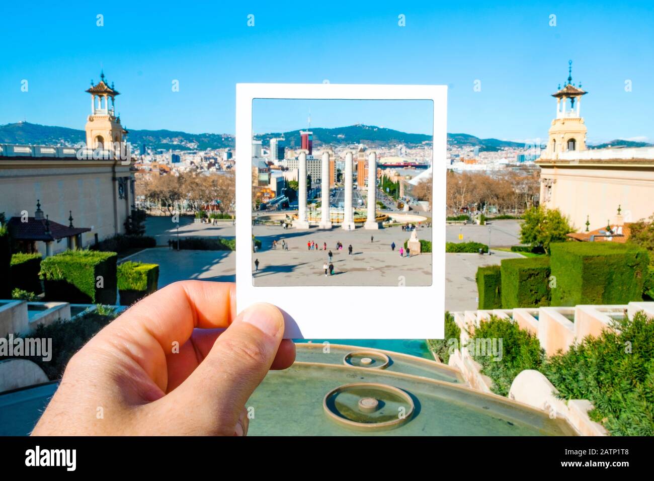 Primo piano di un uomo con una cornice bianca in mano, incorniciando Le Quattro colonne in Montjuic Hill, a Barcellona, in Spagna, simulando una foto istantanea Foto Stock