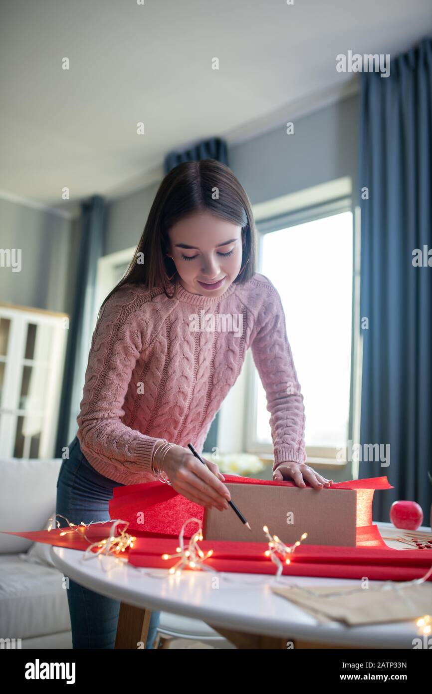 Ragazza dai capelli scuri in una camicia rosa che guarda coinvolta Foto Stock