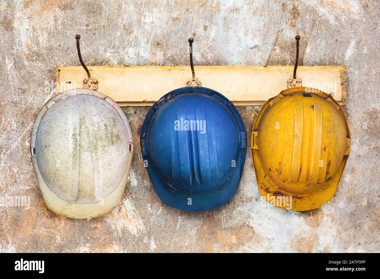 Tre caschi da costruzione appesi su una vecchia rastrelliera in legno Foto Stock