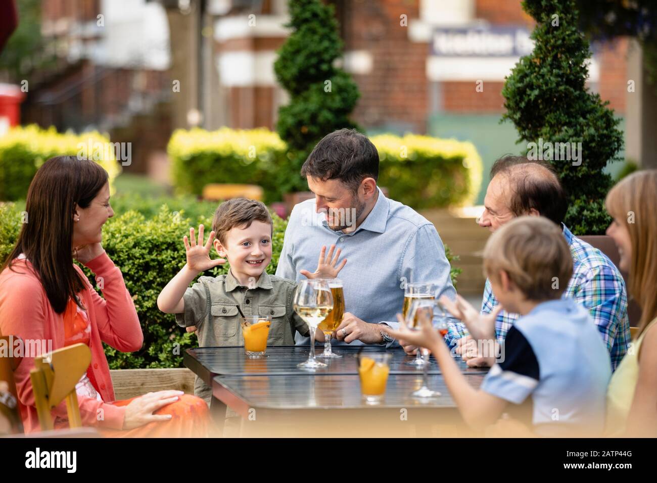 Una famiglia di più generazioni che beve insieme e parla all'aperto in una birreria all'aperto della città. Foto Stock