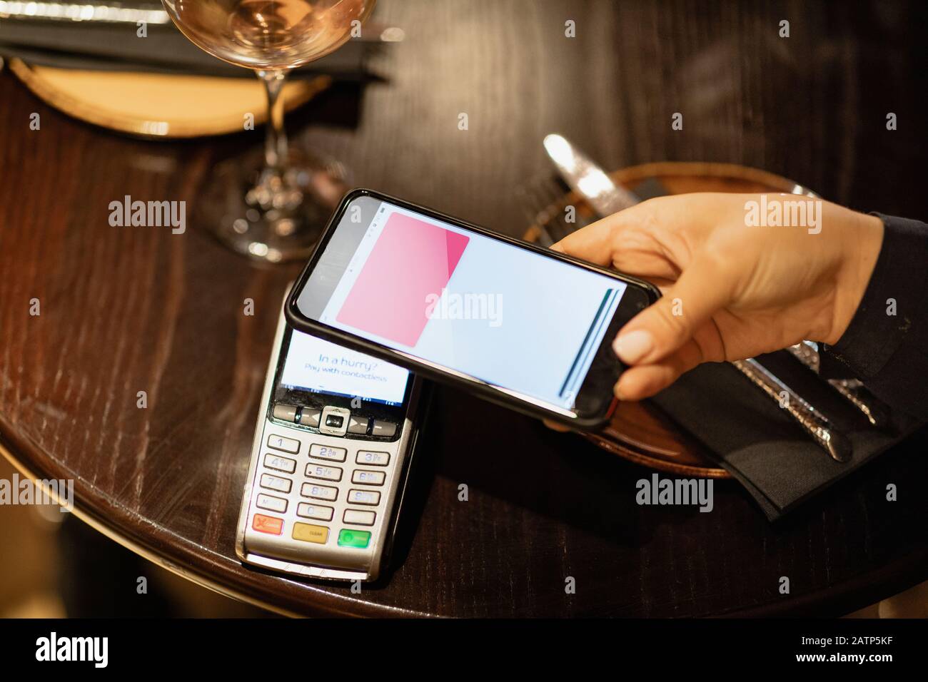 Una persona irriconoscibile che utilizza un telefono cellulare per pagare un pasto. Foto Stock