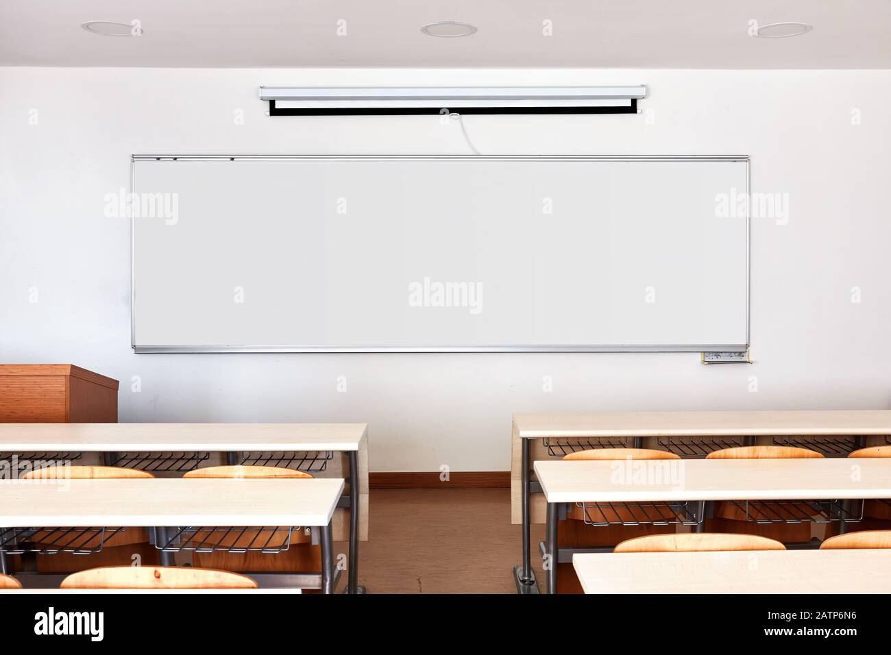 Interni in aula con lavagna bianca, scrivanie in legno e tenda pieghevole per proiettore Foto Stock